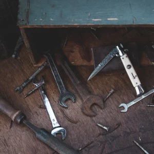 Werkzeuge die verteilt auf dem Boden liegen. Einige unterschiedlich große Maulschlüssel, eine Feile, ein Klappmesser.